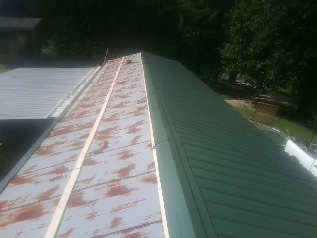 Old rusted panels beside newly installed green metal roofing — Wind Damage Roof Repair by Roofing Brothers in Castleton On Hudson