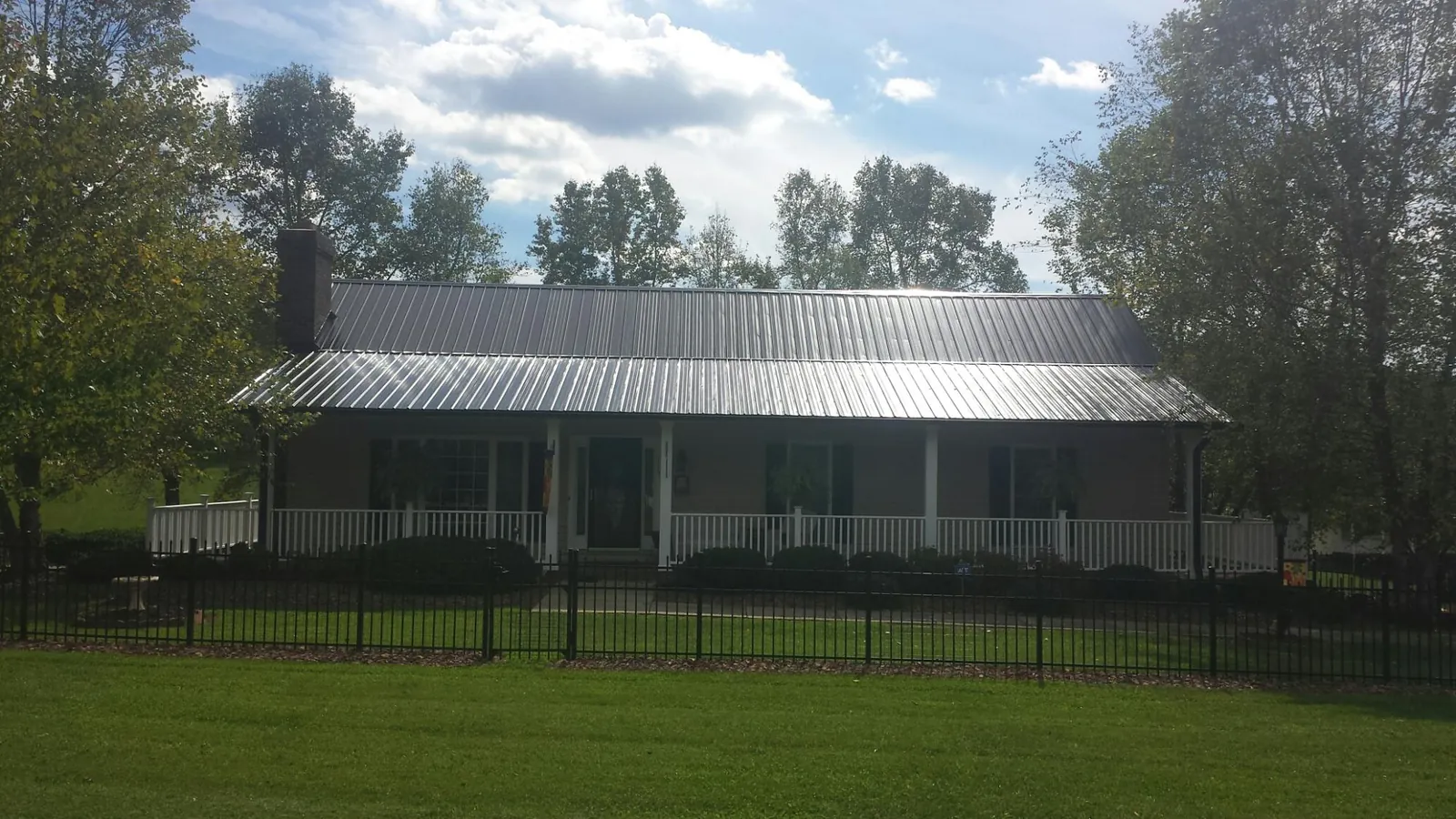 Gray metal roof on a brick ranch with a full width front porch — Gutter Guard Installation work by our crew in Castleton On Hudson