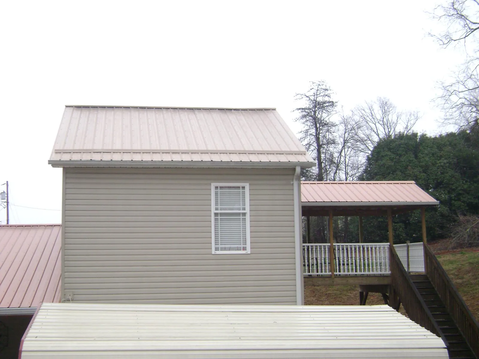 Tan metal roofs on a two story addition and attached porch, from a Roof Replacement job in Castleton On Hudson