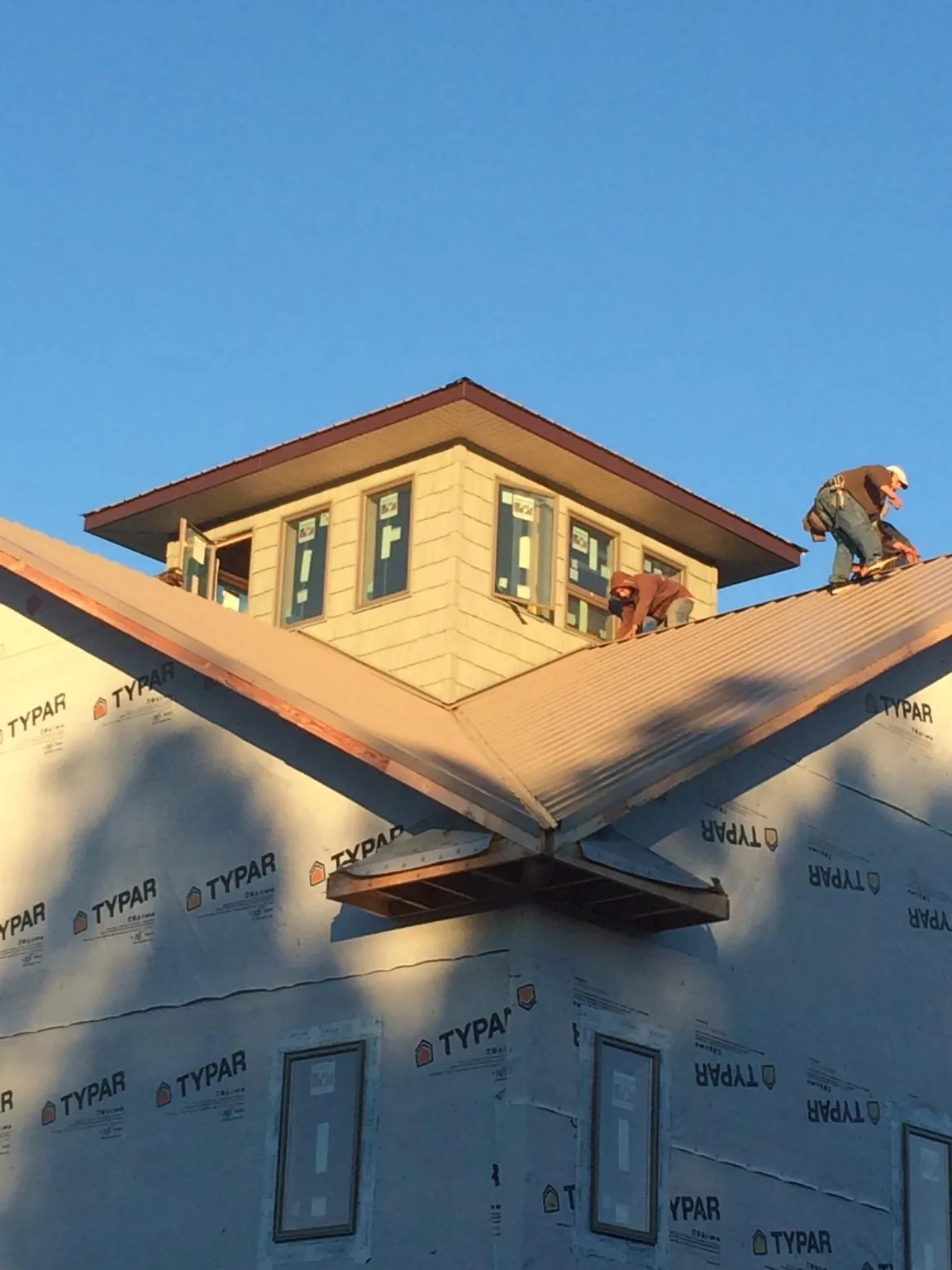 Roofers working around a rooftop cupola on a new metal roof at sunset — Roof Waterproofing in Castleton On Hudson by Roofing Brothers